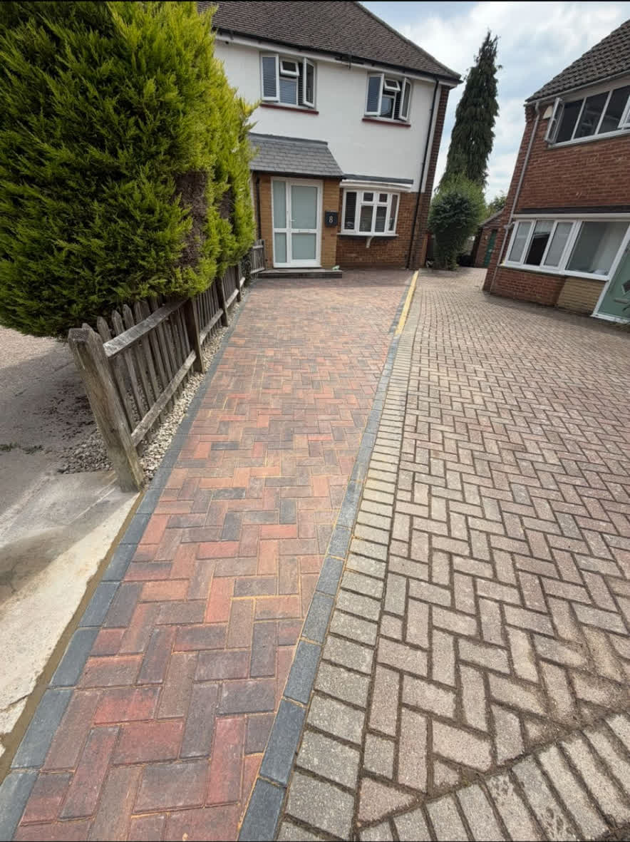 Block paved driveway with red and grey pavers and neat edging in front of a house