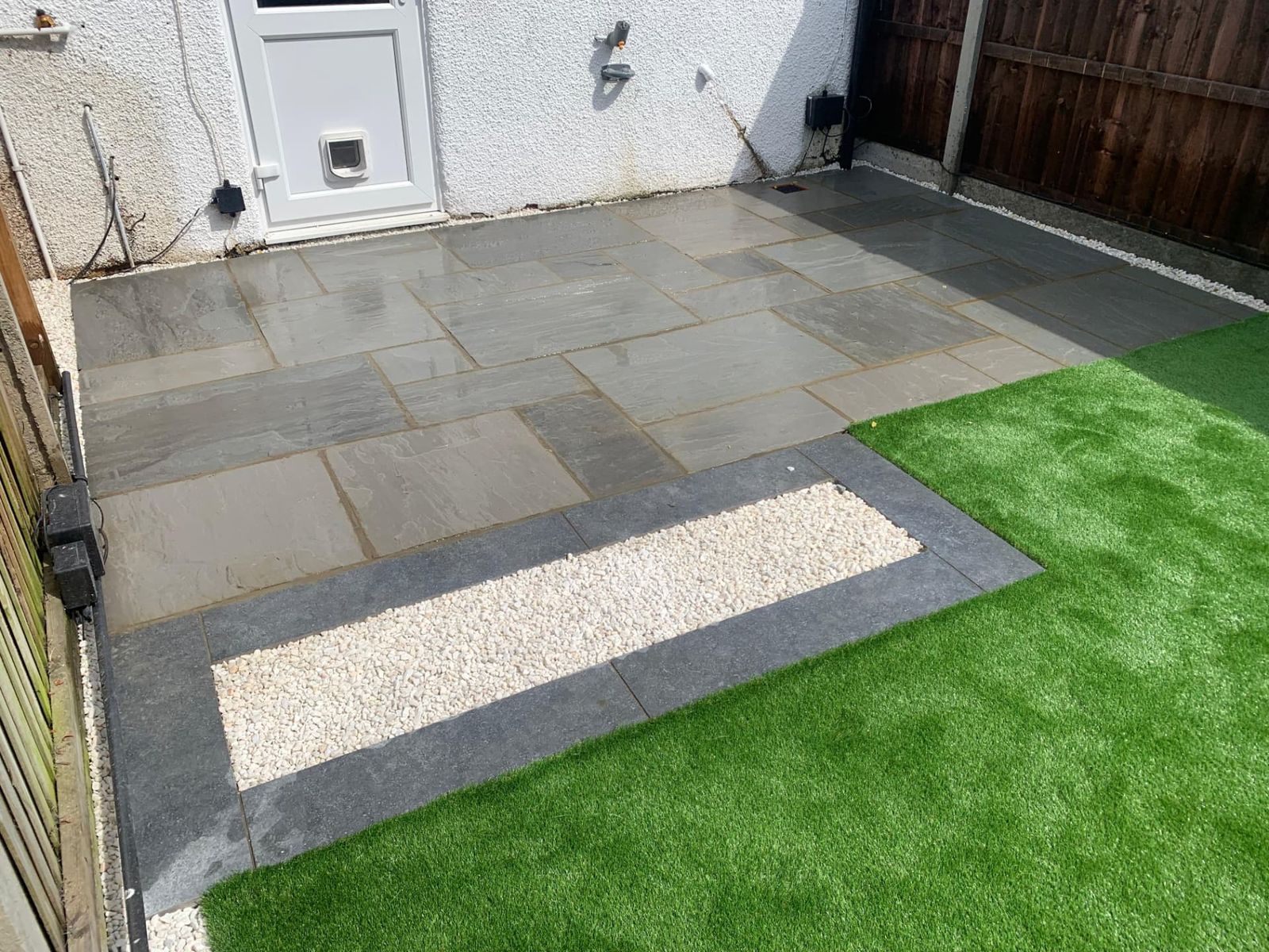 Small garden with artificial grass, grey paving and white gravel inset