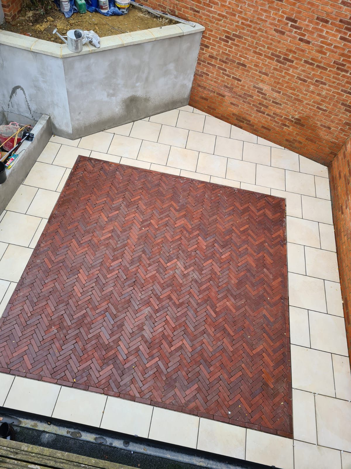 Courtyard with pale paving around a red brick herringbone centre