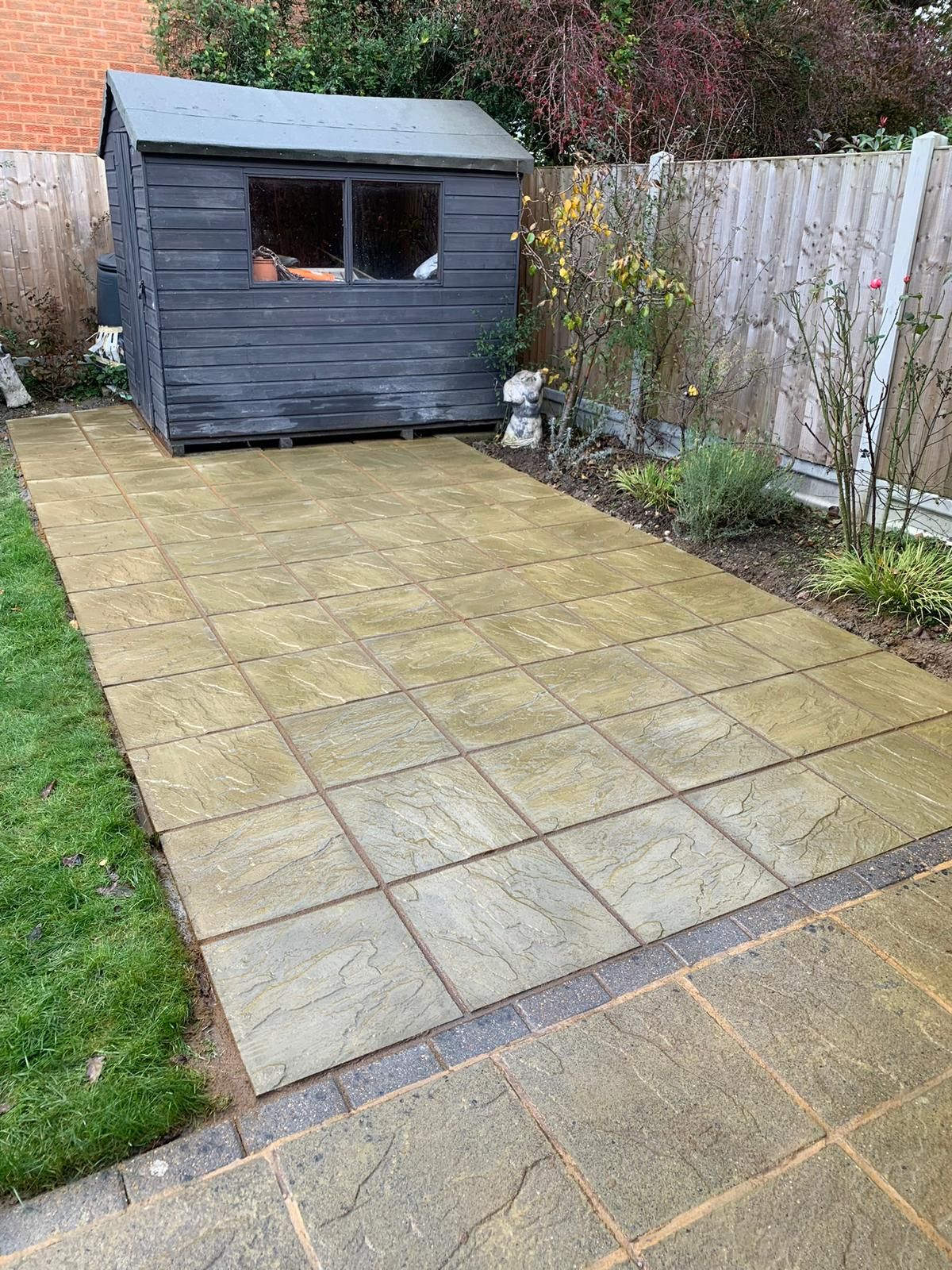 Buff sandstone path and patio leading to a garden shed