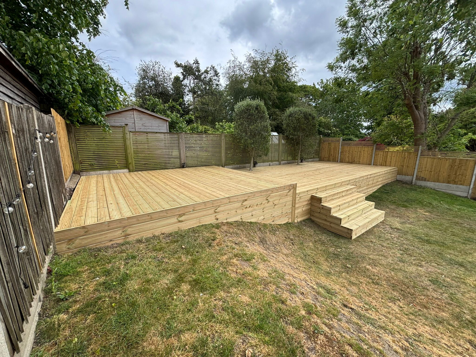 Raised timber decking with stepped access and slatted fencing