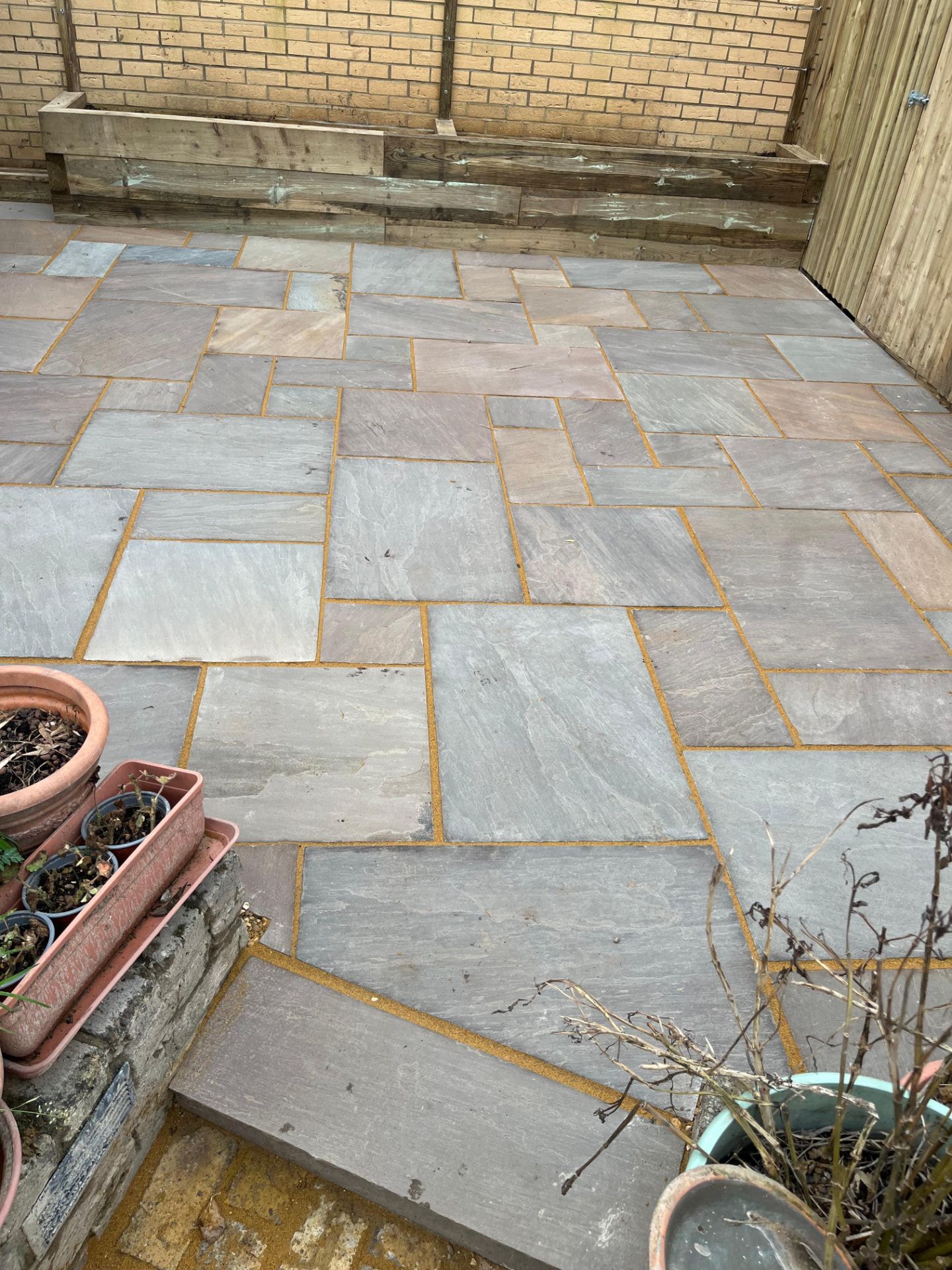 Mixed-size Indian sandstone patio with raised sleeper edging